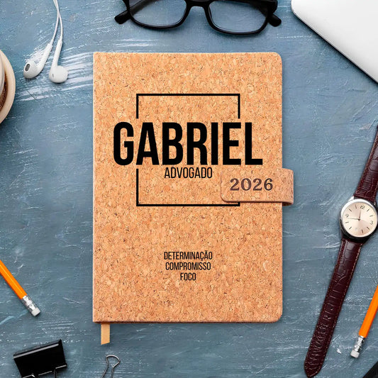 Agenda diária 2026 personalizada com nome e profissão. Capa em cortiça com fecho magnético, formato A5.