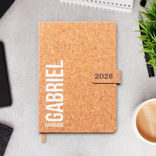 Agenda diária 2026 personalizada com nome e profissão. Capa em cortiça com fecho magnético, formato A5.