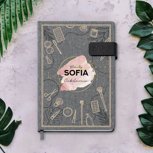 Agenda diária 2026 personalizada com nome e profissão. Capa em tecido com fecho magnético, formato A5.