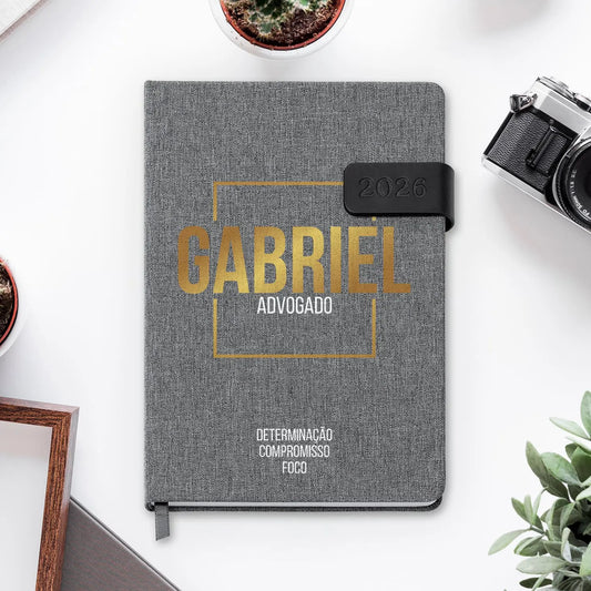 Agenda diária 2026 personalizada com nome e profissão. Capa em tecido com fecho magnético, formato A5.
