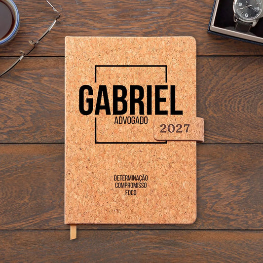 Agenda diária 2027 personalizada com nome e profissão. Capa em cortiça com fecho magnético, formato A5.