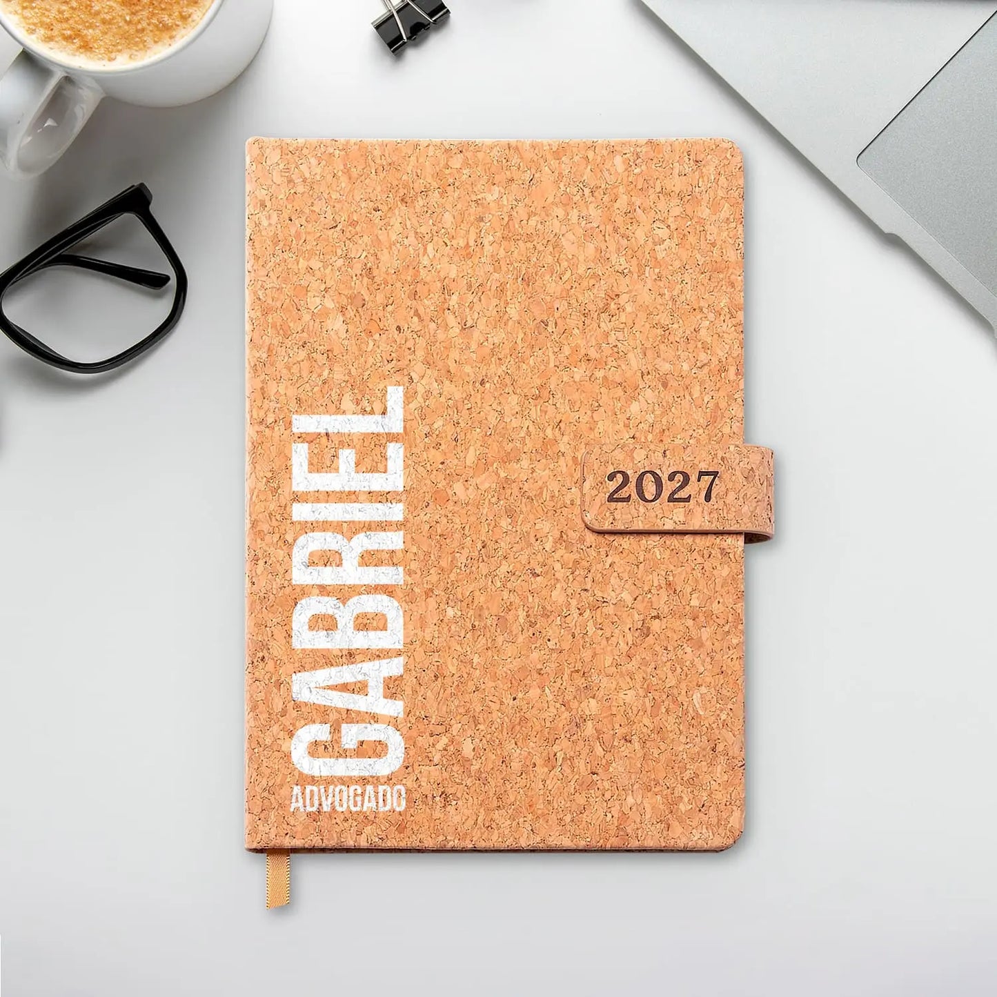 Agenda diária 2027 personalizada com nome e profissão. Capa em cortiça com fecho magnético, formato A5.