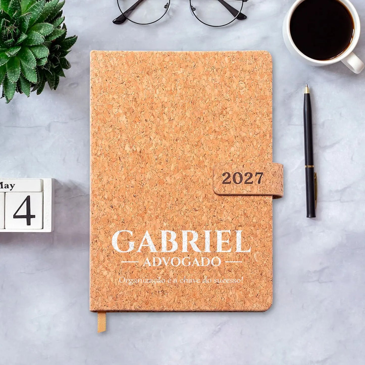 Agenda diária 2027 personalizada com nome, profissão e frase. Capa em cortiça com fecho magnético, formato A5.