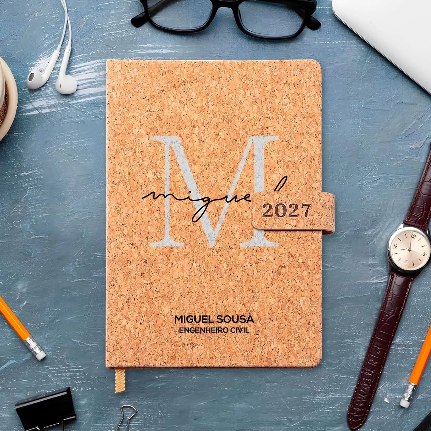 Agenda diária 2027 personalizada com nome e profissão. Capa em cortiça com fecho magnético, formato A5.