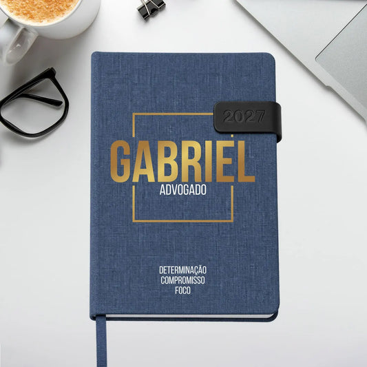 Agenda diária 2027 personalizada com nome e profissão. Capa em tecido com fecho magnético, formato A5.