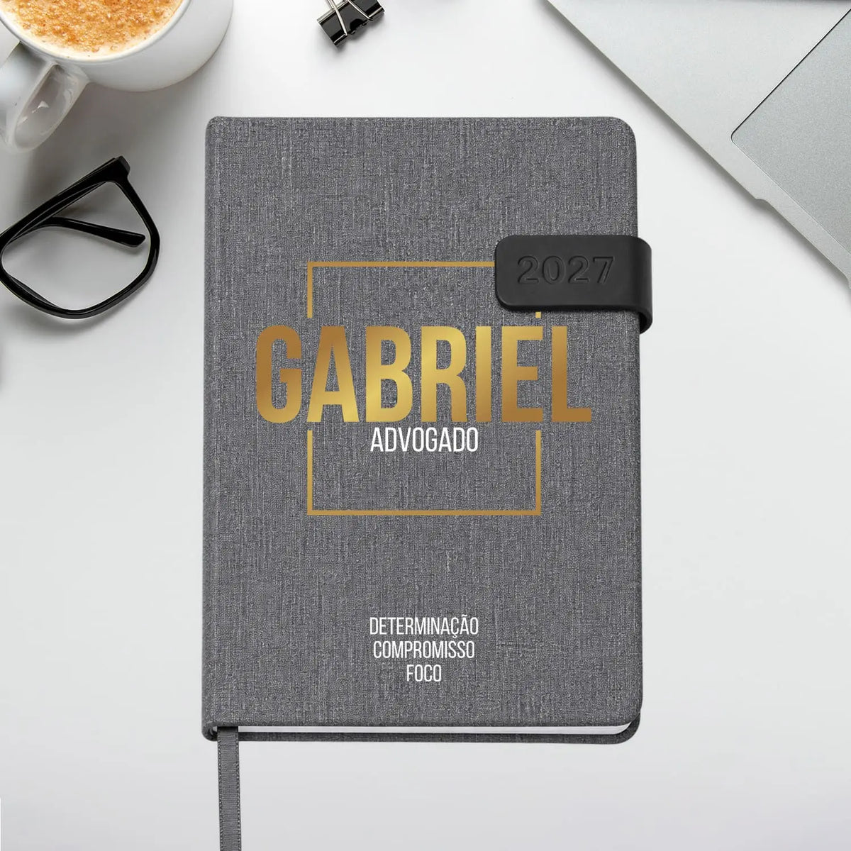 Agenda diária 2027 personalizada com nome e profissão. Capa em tecido com fecho magnético, formato A5.