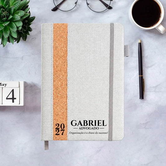 Agenda diária 2027 personalizada com nome, profissão e frase. Capa em linho e cortiça, formato A5.